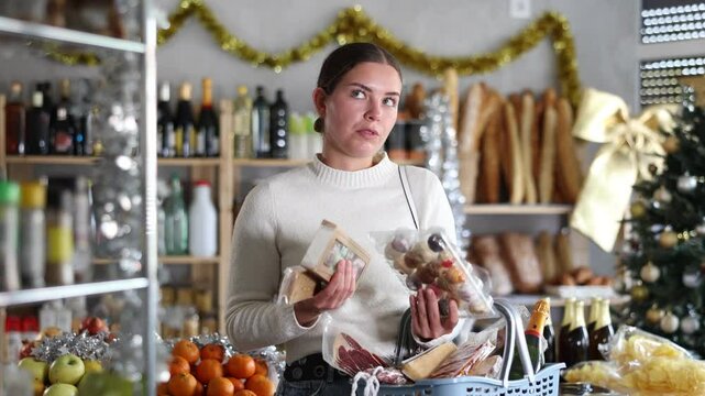 In festive little store decorated with Christmas tree and shiny tinsel, smiling young woman picking out rich nutty turron and colorful panellets, imagining joy of indulging in sweet delight. High