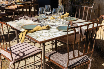 restaurant table in the sun with beautiful dishes and wine glasses