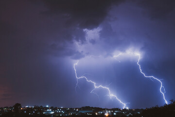 A stunning photograph of a lightning strike over a suburban area during a vibrant sunset, featuring...