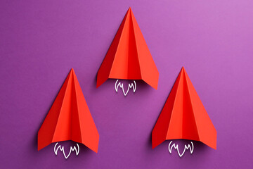 Red paper planes rushing forward on purple background