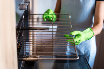 Woman cleaning oven racks in a modern kitchen during housework