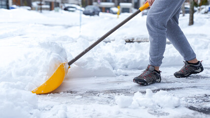 Man shoveling snow off of his driveway after a winter storm in Canada. Man with snow shovel cleans...