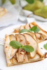 Pieces of tasty puff pastry pie with pears and mint on table, closeup