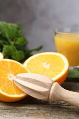 Juicer and fresh oranges on wooden table, closeup