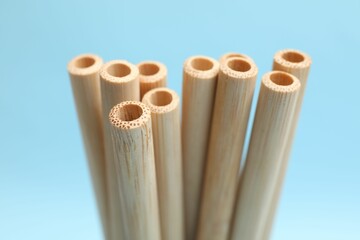 Bamboo drinking straws on light blue background, closeup