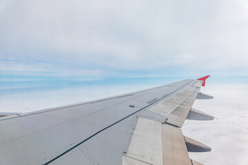 View from the airplane window at a beautiful cloudy sky and the airplane wing