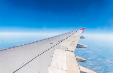 View from the airplane window at a beautiful cloudy sky and the airplane wing