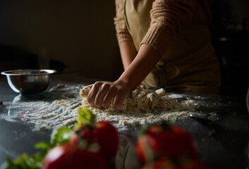 Person kneading dough on a floured surface in a warm kitchen setting