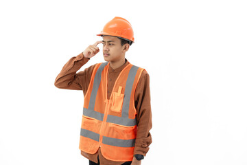 Young Indonesian male construction worker in full safety gear looking thoughtful with index finger touching forehead, industrial and construction concept, isolated on white background.