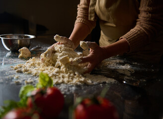 Person kneading dough in a kitchen with fresh ingredients nearby