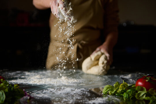 Chef preparing dough with fresh ingredients in a rustic kitchen setting