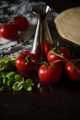 Fresh tomatoes and herbs on a dark wooden kitchen counter