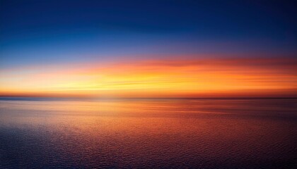 Obraz premium Golden Hour Sea: A breathtaking view of the sun setting over a calm sea, casting a warm glow across the horizon. The sky is a vibrant mix of orange, yellow, and blue.