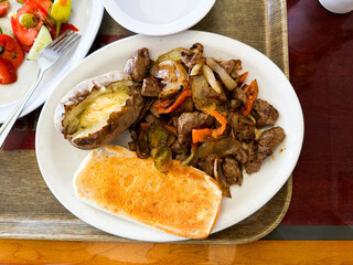Delicious meal featuring grilled beef, vegetables, baked potato, and toast served at local eatery during lunchtime