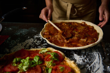 Chef preparing homemade pizza with tomato sauce and fresh ingredients