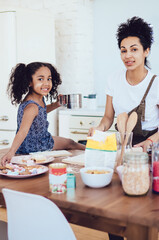 Ethnic mother and daughter baking at home