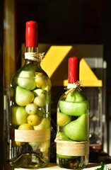 Pickled pears in liquid in clear glass bottles sealed with red wax on sunny windowsill