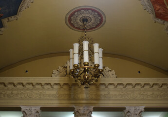 Beautiful antique chandelier on the ceiling with stucco and painting.