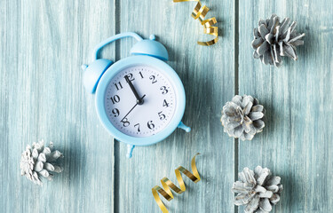 Close up of pine cones with blue alarm clock on stylish wooden table with copy space.