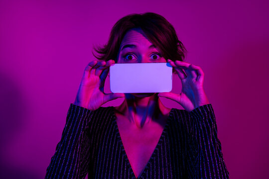 Photo portrait of attractive young woman cover mouth white screen wear trendy overall clothes isolated on neon light pink color background