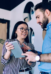 Optimistic partners browsing tablet in business center