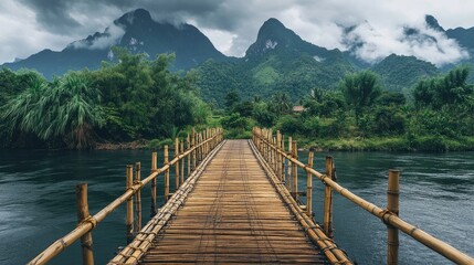 Fototapeta premium Serene Bamboo Bridge Over Calm Water with Misty Mountain Background