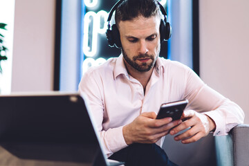 Caucasian freelancer in electronic equipment listening business book during time for remote work...