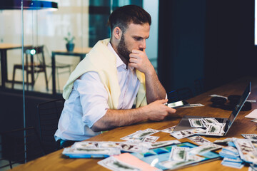 Side view of successful businessman checking income earnings in online web sport betting sitting at table desktop with modern laptop computer near mockup backdrop on wall, Caucasian man making money