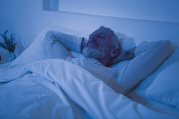 Elderly man enjoying a peaceful morning in bed, relaxing at home, immersed in comfort and...