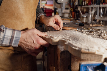 Luthier using gouge while crafting violin in workshop