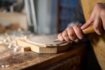 Luthier carefully carving wood for violin making in workshop