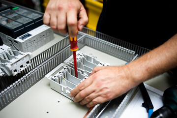 Electrician, engineer assembles an electrical cabinet in a factory.