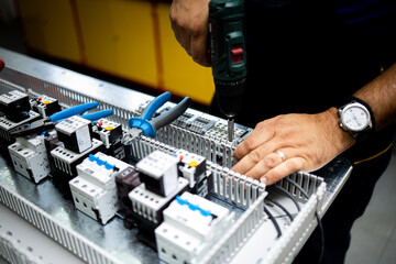 Electrician, engineer assembles an electrical cabinet in a factory.