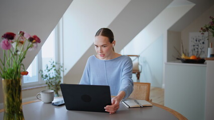 Videocalling student waving hand inserting wireless earphones at flat closeup