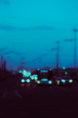 A blurry image of a nighttime highway, with cars driving along it with their headlights on, creating a scene of nighttime traffic.