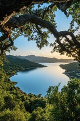 Stunning View of Cretan Lake Framed by Oak Tree Branch with Blue Sky and Greenery