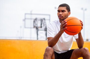 Young man with a ball in hands sitting with a serious look