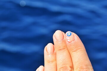 Naklejka premium hand, fingers above water, fingers and painted nail with the eye of the prophet, eye of the prophet painted on nail