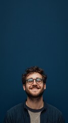 Fototapeta premium nerdy man with glasses smiling at camera on dark blue background with copy space vertically 9:16