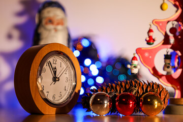 On Christmas Eve, there is a clock, a pine cone, Santa, Christmas tree decorations, Christmas lights and a tabletop Christmas tree on the table.