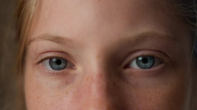 Close up little girl opening blue eyes looking at camera blinking Caucasian serious angry child teenage kid schoolgirl pupil student eyebrows frowning upset expression offense custody childcare indoor