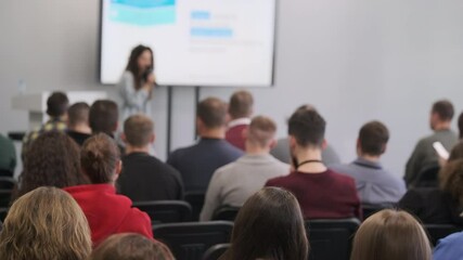 Audience attentively listens to speaker during business seminar presentation in conference room setting