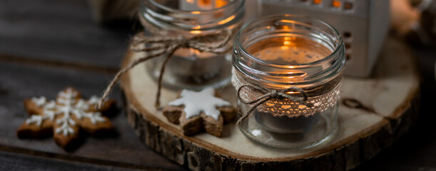Banner. Aromatic christmas handmade candle with sweet scent of gingerbread cookies. Cozy holiday home atmosphere, aromatherapy. Interior composition with burning candles, anise, cinnamon, pine cones