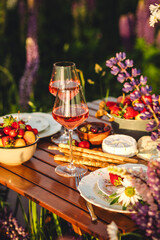Perfect surprise date for loving couple, private wedding, romantic marriage proposal. Summer, sunset, golden hour. Appetisers. Beautiful elegant outdoor arrangement in meadow with purple blue lupins