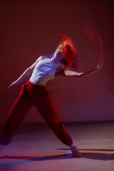 A young woman dances contemporary dances in blue and red light. Long exposure. Vertical photo. 