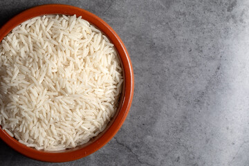 Earthenware bowl full of Basmati Rice on a kitchen countertop in a zenithal photograph
