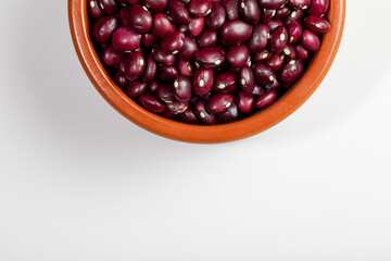 Earthenware bowl full of red beans from Anguiano on a white kitchen worktop in a zenithal photograph.