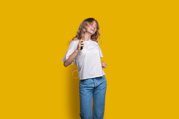 A Joyful Young Woman Energetically Dancing Against a Bright and Lively Yellow Background