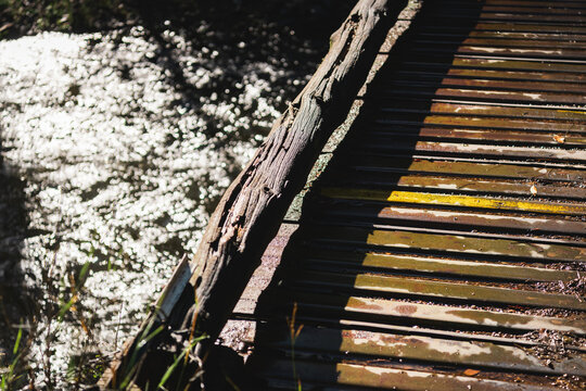 Detail of a rustic wooden footbridge above the sparkling waters of the Pecos River, New Mexico