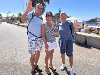 Group of three seniors smiling people outdoors with sea view on background Enjoying Vacation and Freedom in a sunny day. Happy Retirement Lifestyle Concept